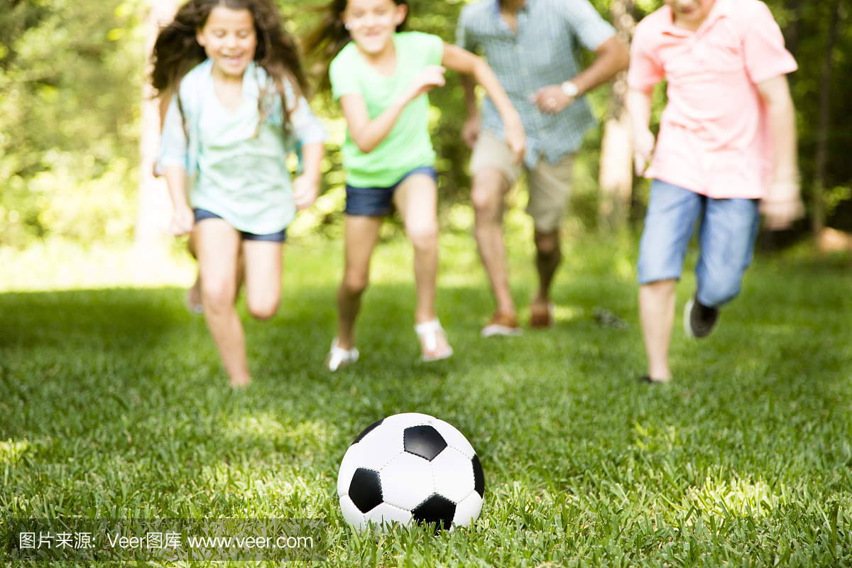 家庭户外夏季踢足球游戏。公园。