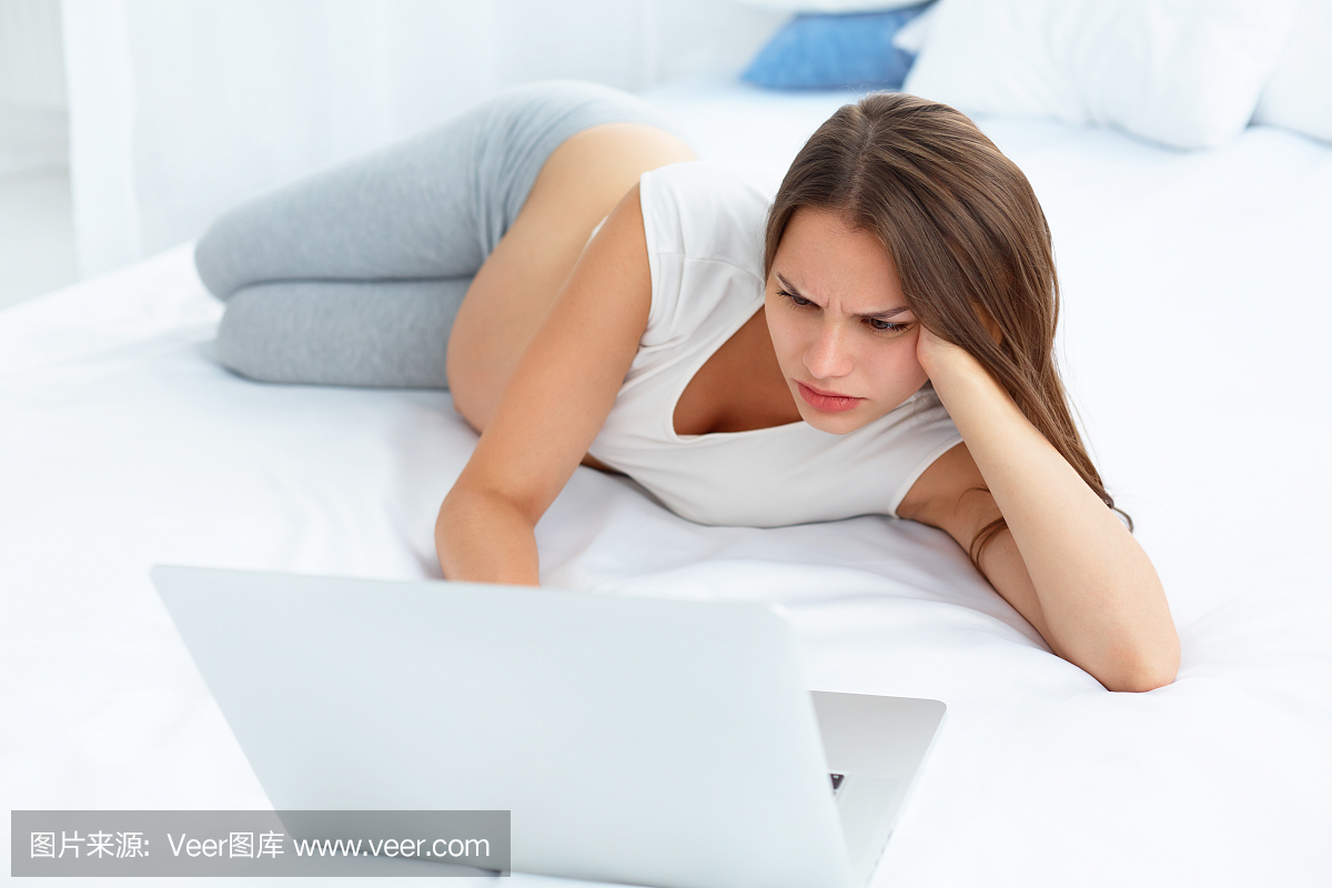 沮丧的孕妇在笔记本电脑工作时躺在