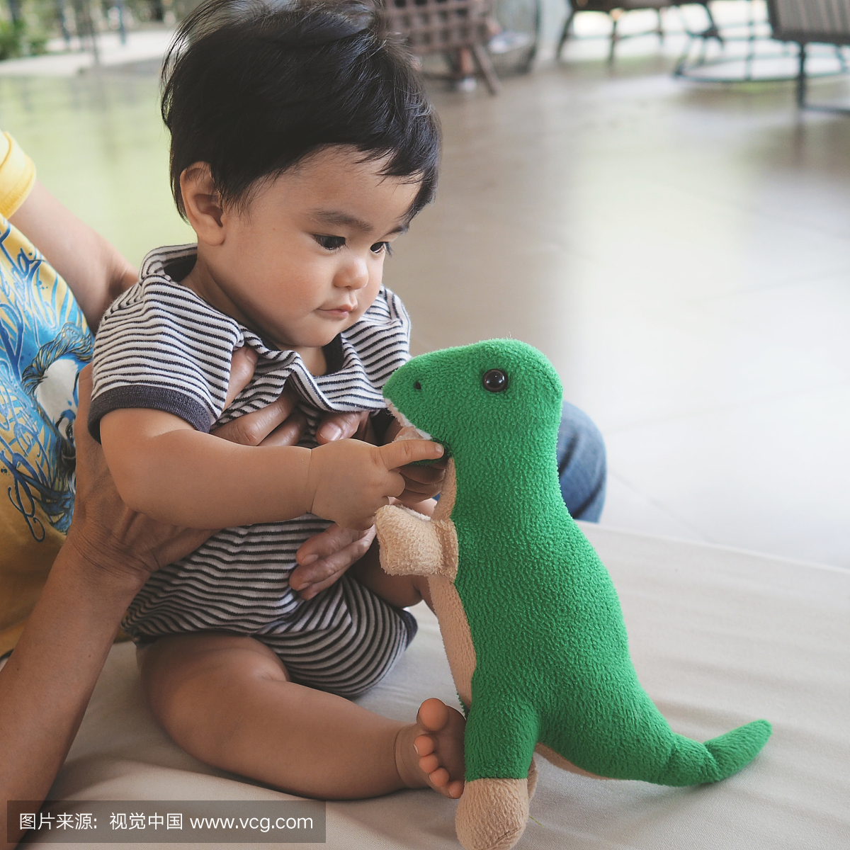 九个月大的男孩玩毛绒玩具恐龙