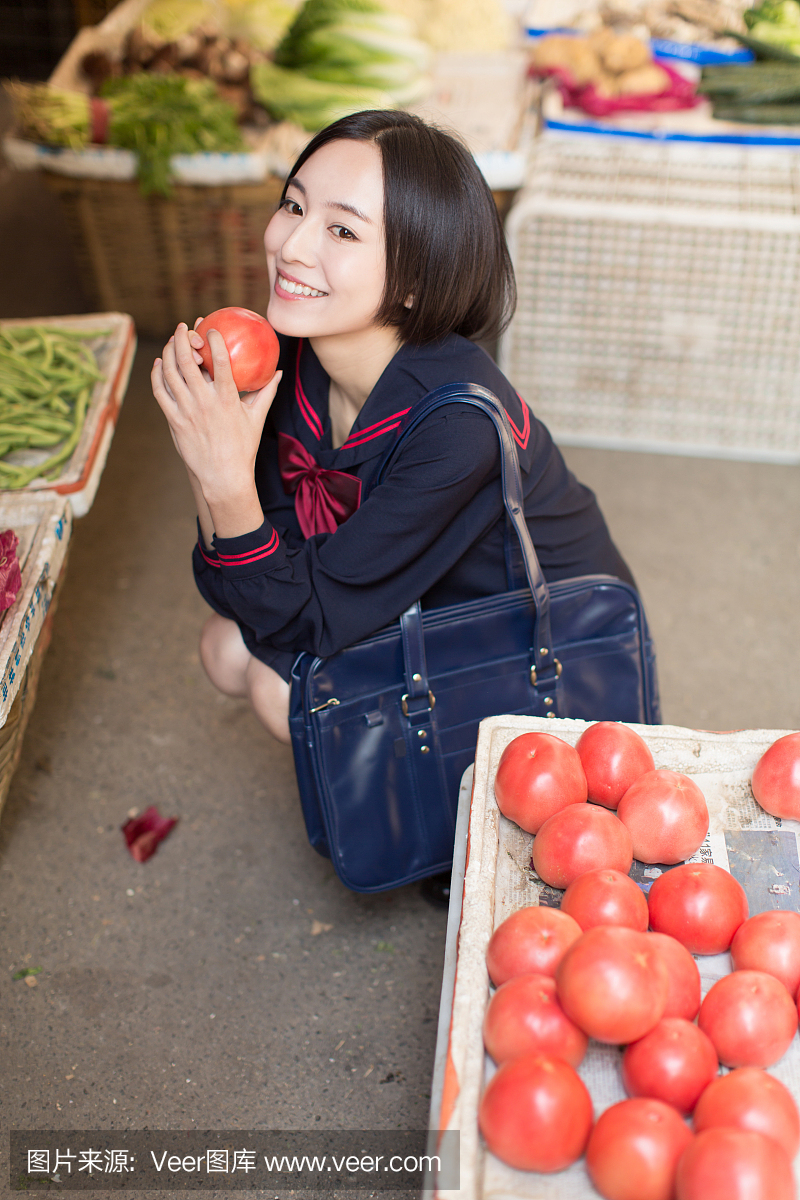 美丽的中国女学生在市场上买水果和蔬菜