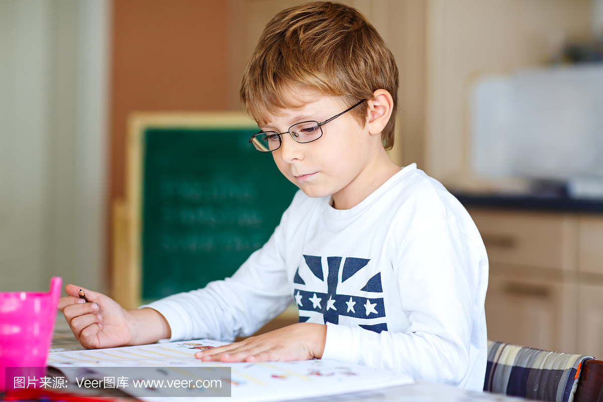 快乐的学校小孩男孩戴眼镜在家做作业