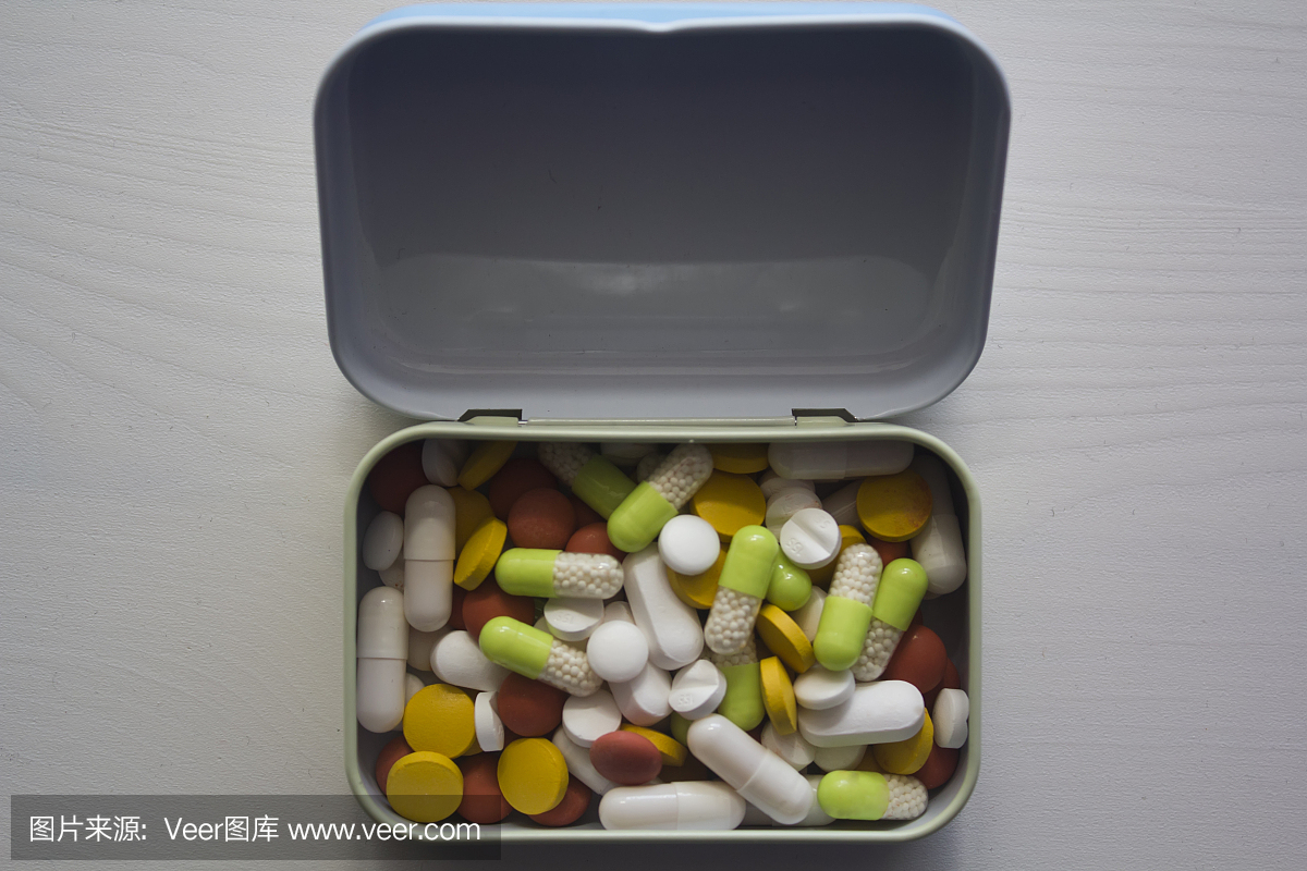 不同颜色的药丸在木桌上的金属盒子里面