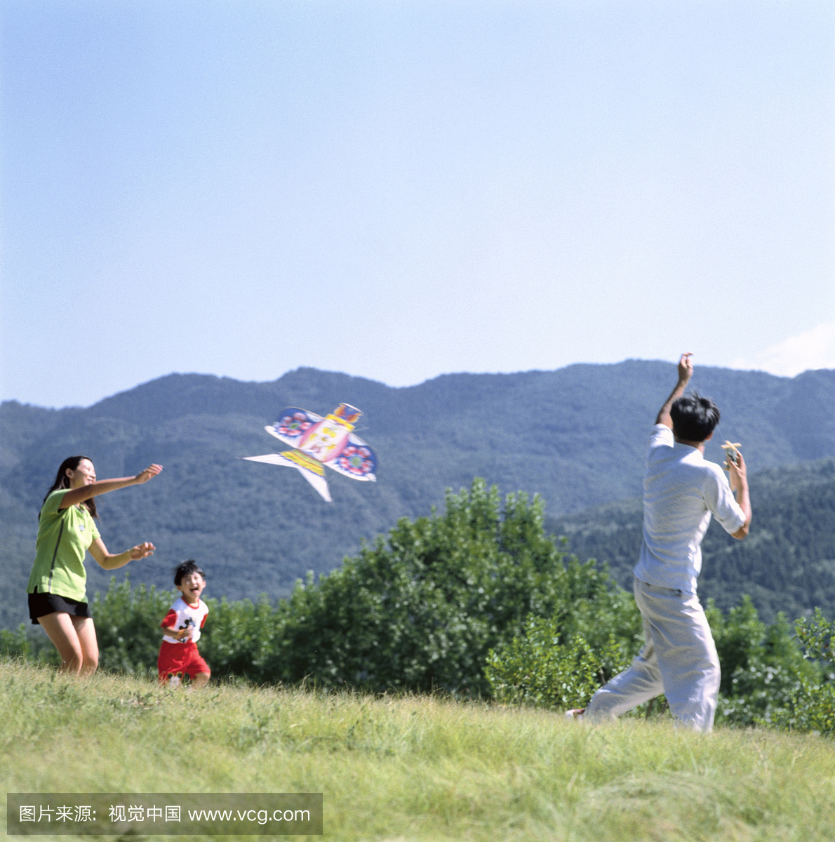 东方家庭在户外草地上放风筝