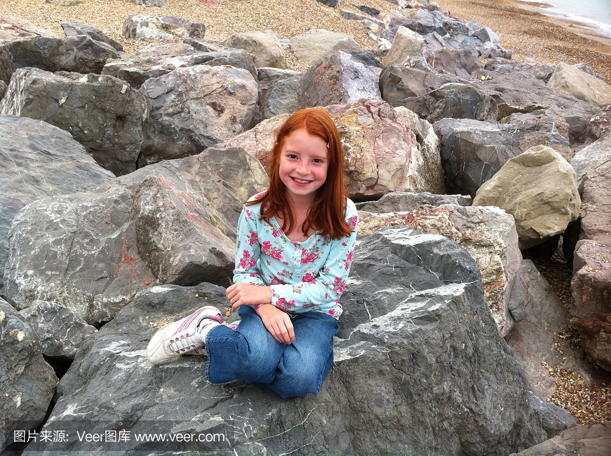 女孩在小美人鱼姿势在岩石上的形象