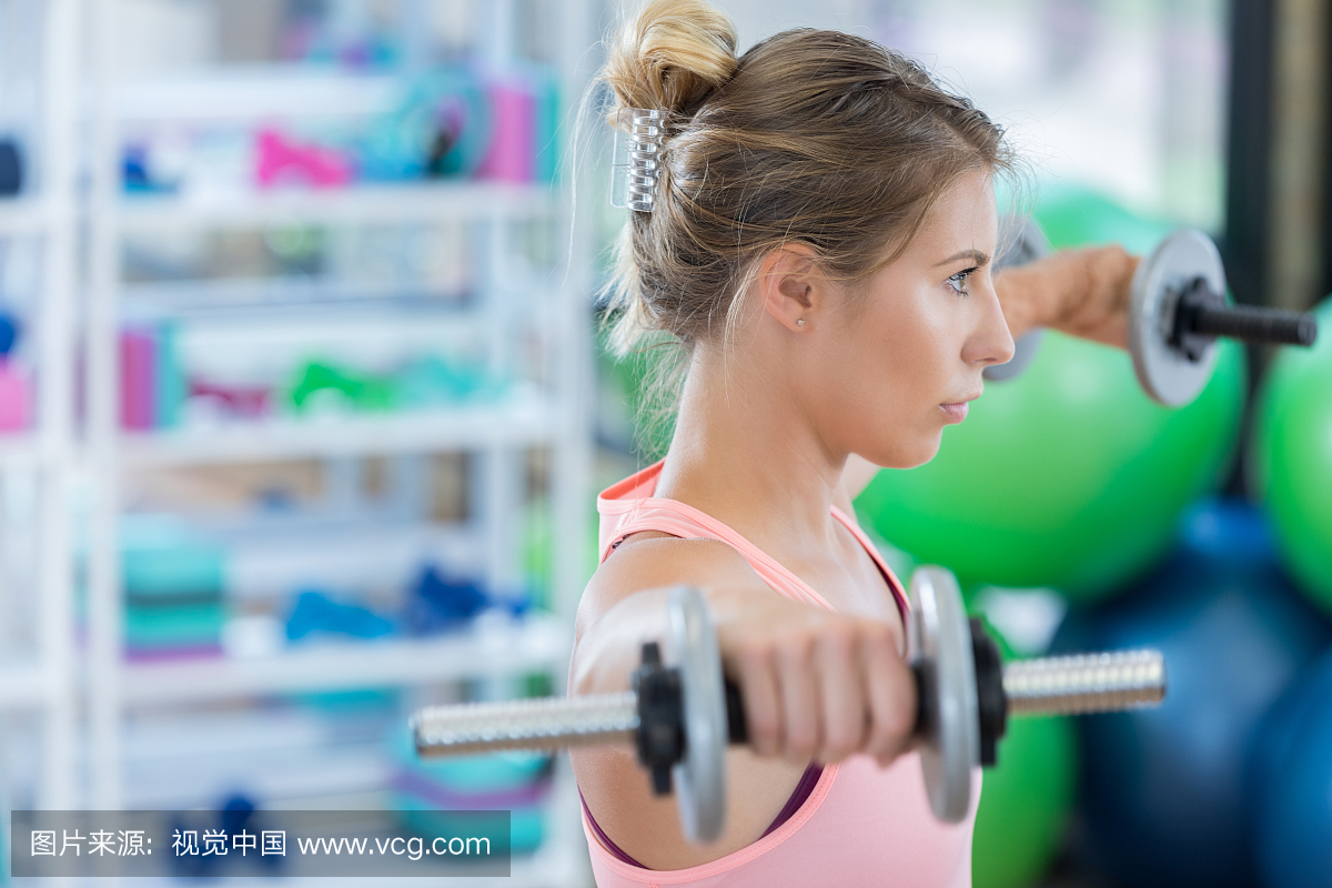 女子在健身房锻炼肩膀与自由重量