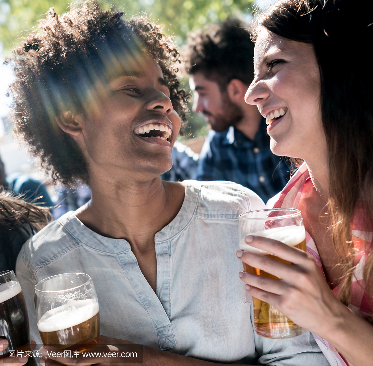 令人惊叹的黑人和白人朋友在酒吧享受啤酒和笑