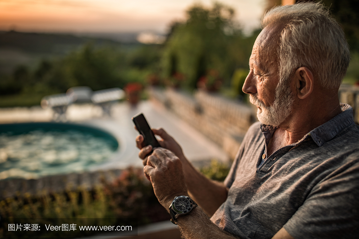 一位老人发短信在户外手机的配置文件视图。