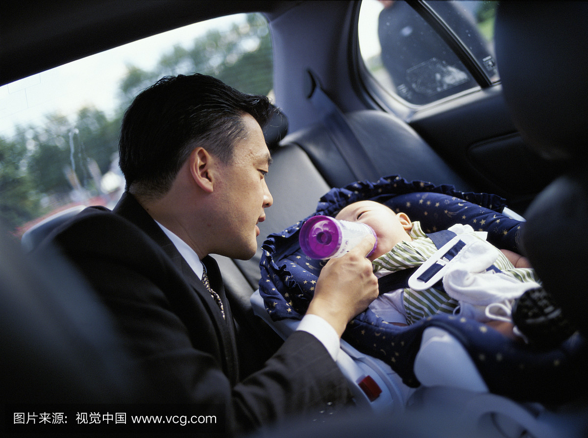 父亲喂婴儿(3-6个月)在汽车座椅上