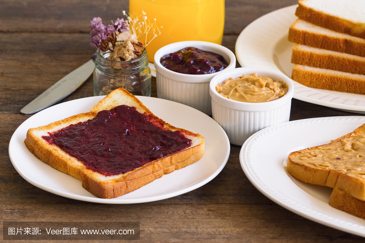 吐司面包配自制草莓果酱和花生酱配橙汁。自制