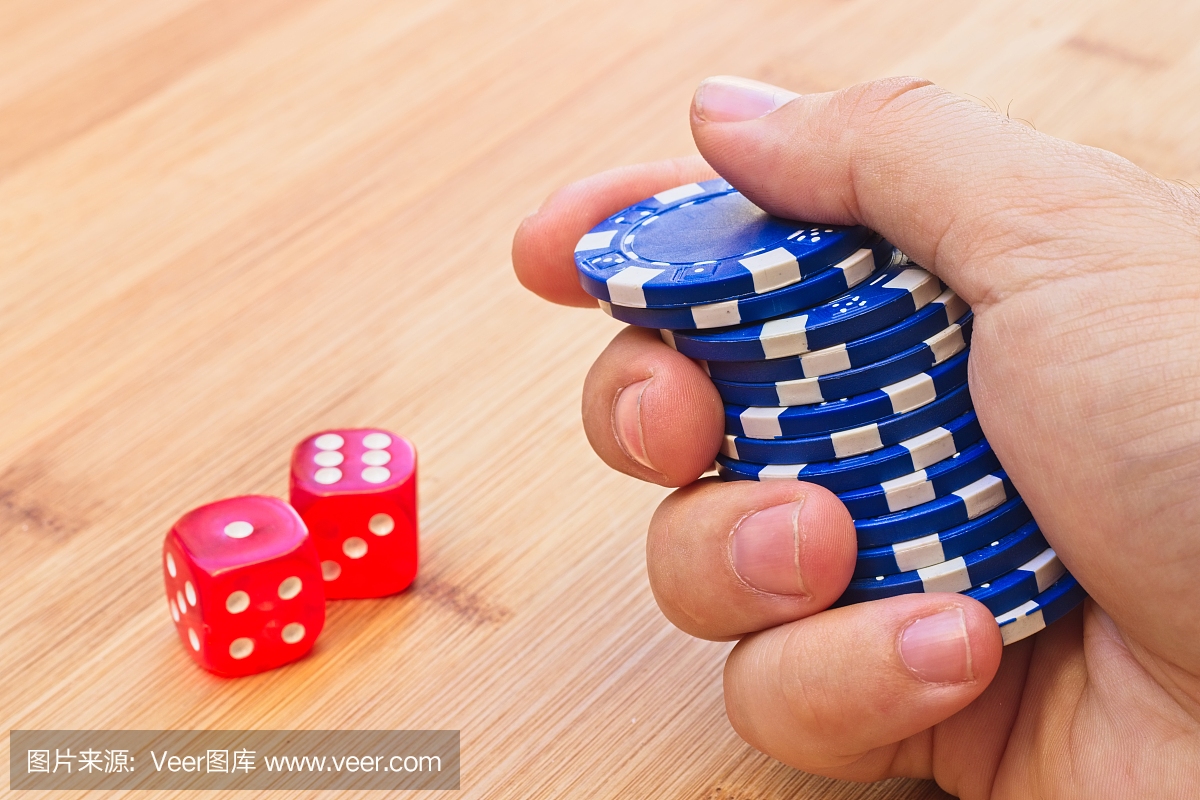 赌博概念图像组成的手拿着赌场芯片和掷骰子。