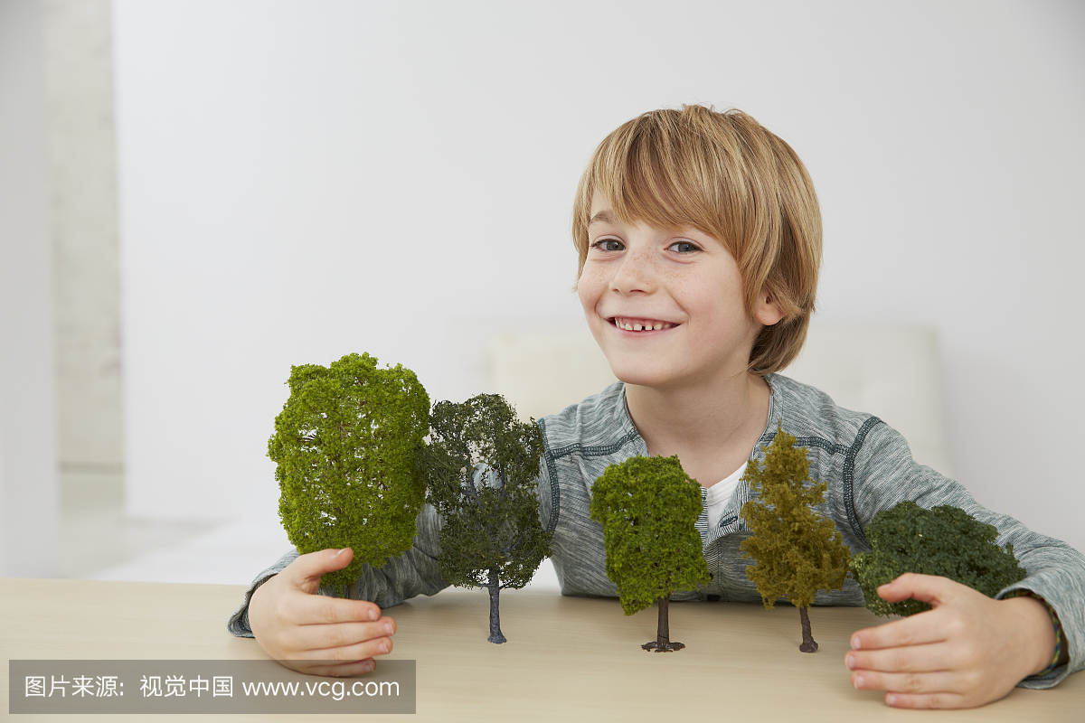 德国,男孩坐在桌上与树模型,环境保护