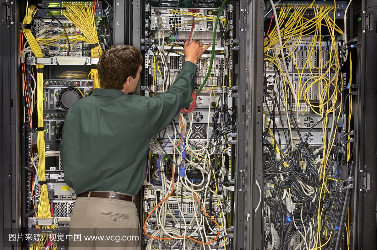 技术员在计算机网络设备机架上工作,后视图