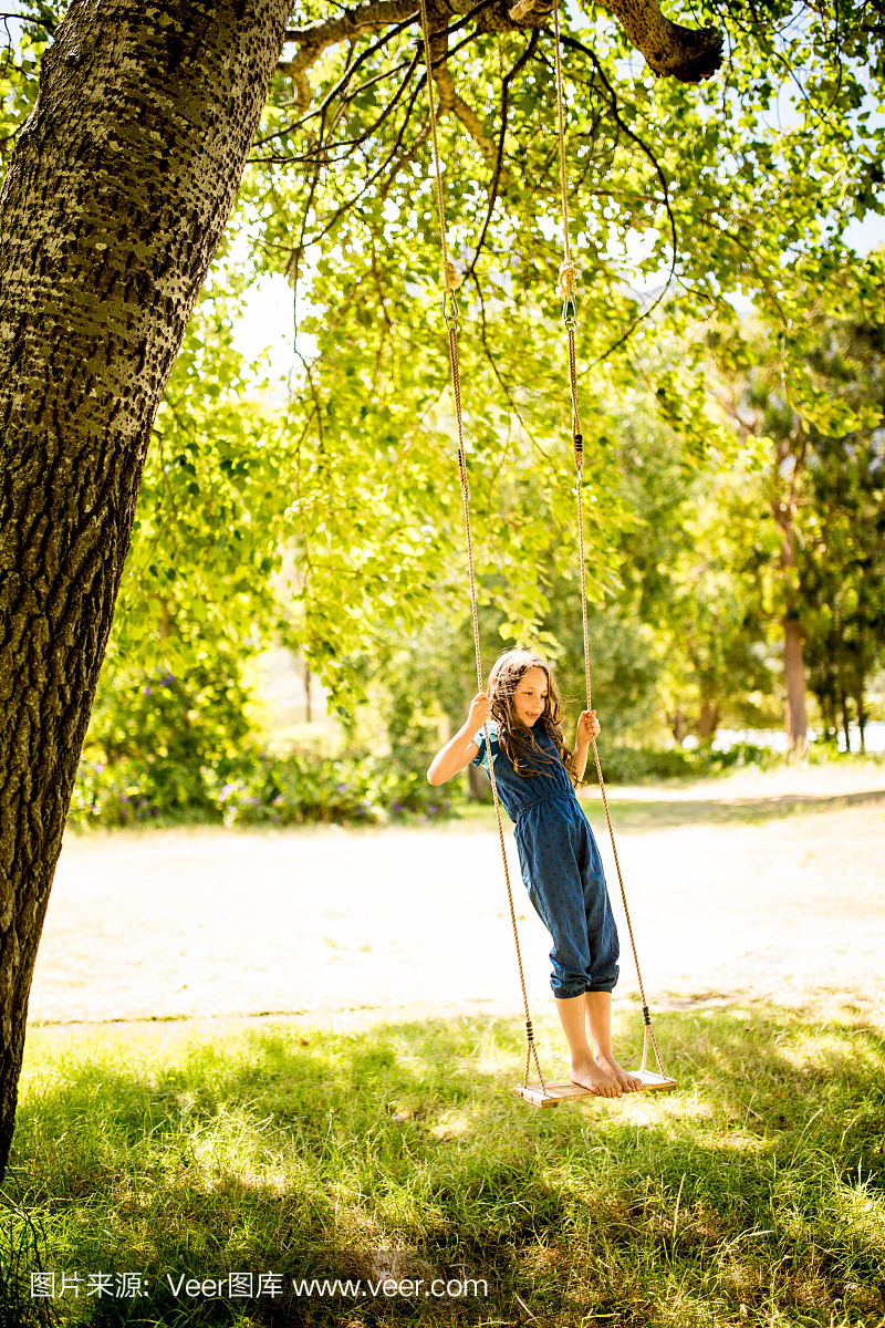 女孩站在秋天在大树下在阳光照射的领域