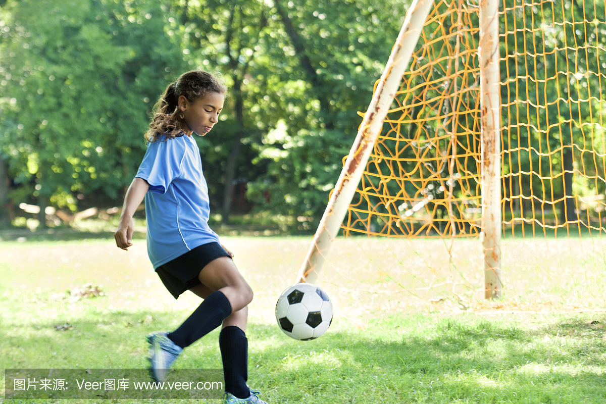 年轻女子运动员将足球踢进球门