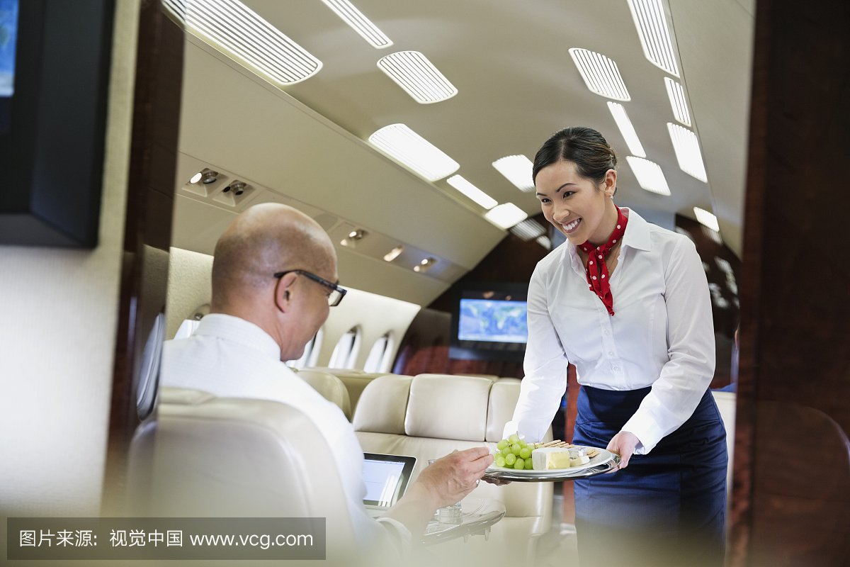 乘务员为飞机上的男性乘客提供食物