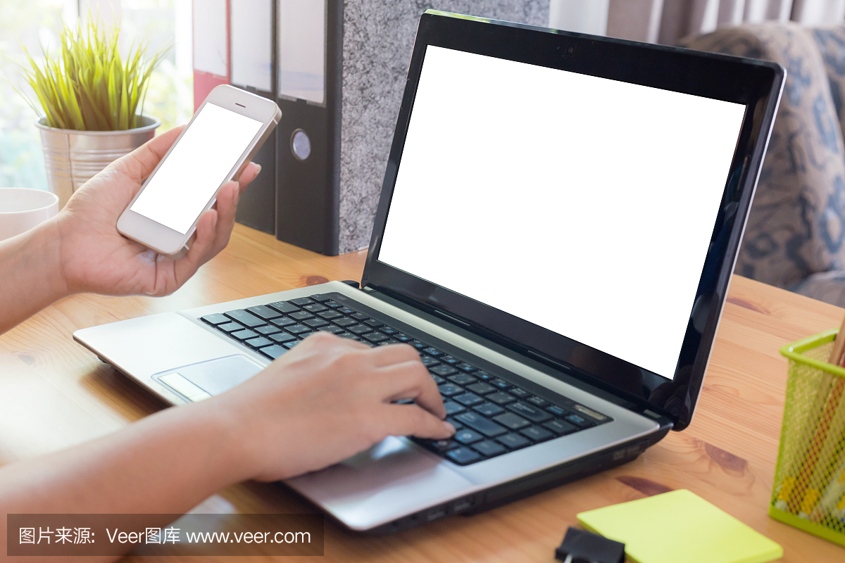 年轻女子在家里使用智能手机和笔记本电脑工作