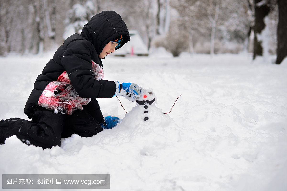 小男孩在冬天做个雪人