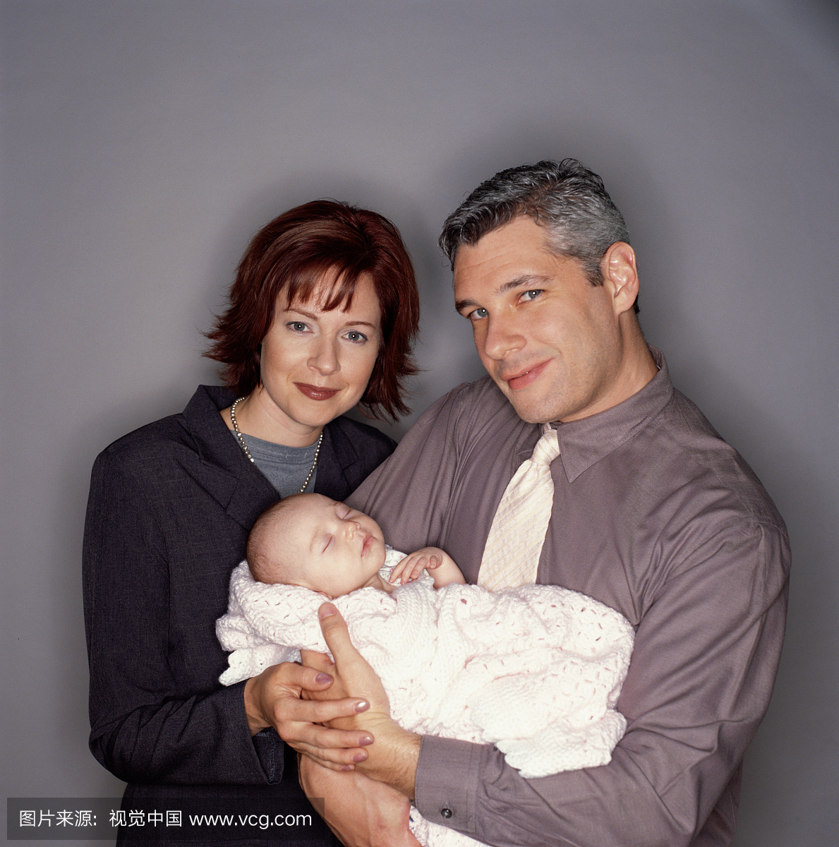母亲和父亲在商务套装抱着婴儿(1-3个月)