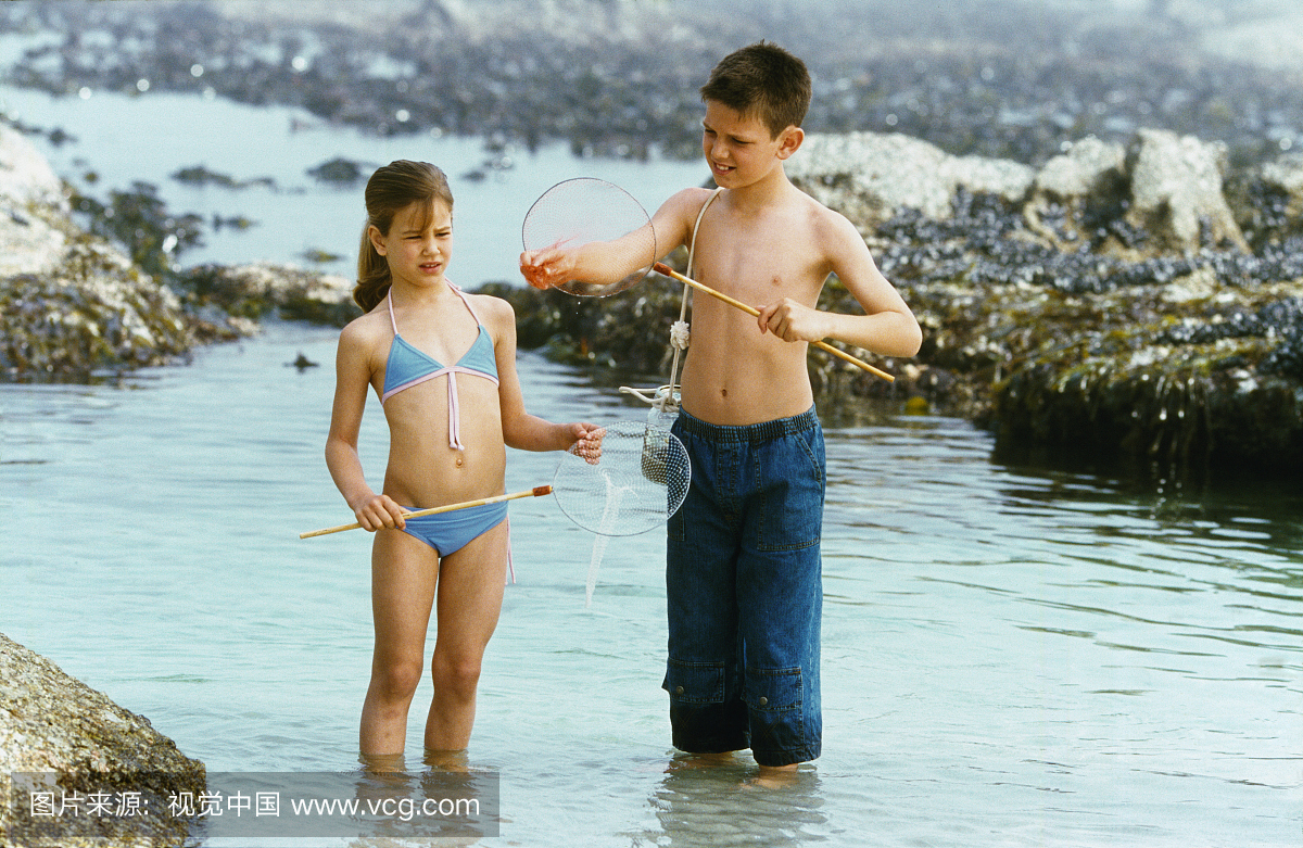 男孩(10-11)和女孩(8-9)在岩石池中钓鱼