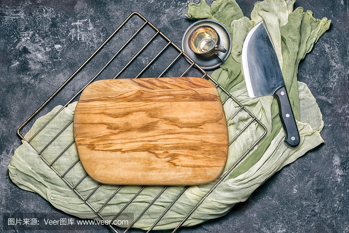 空白的橄榄木菜板上烤架和深色黑色水泥背景所
