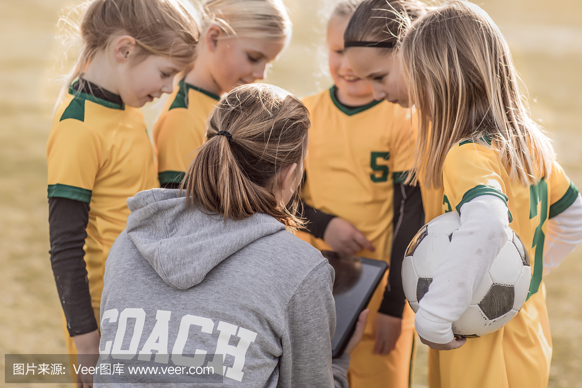 年轻的金发女子足球教练和她的女孩足球队