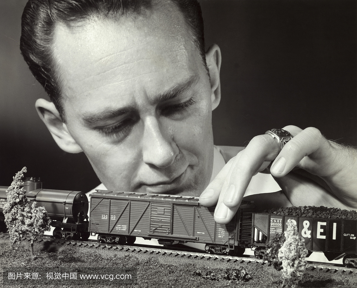 特写镜头的中年成年男子拿着一个玩具火车的模