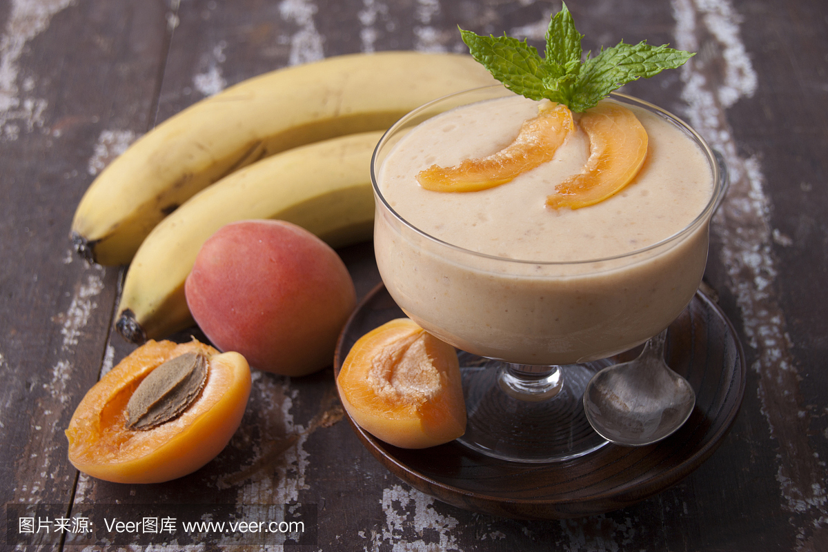 与杏和香蕉在旧木桌上的花瓶里的冰沙