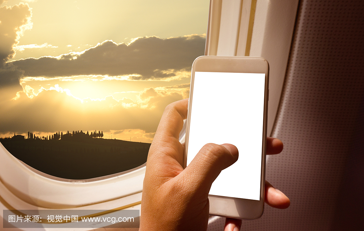 拿着黑屏智能手机的商人手在飞机上靠窗座位和