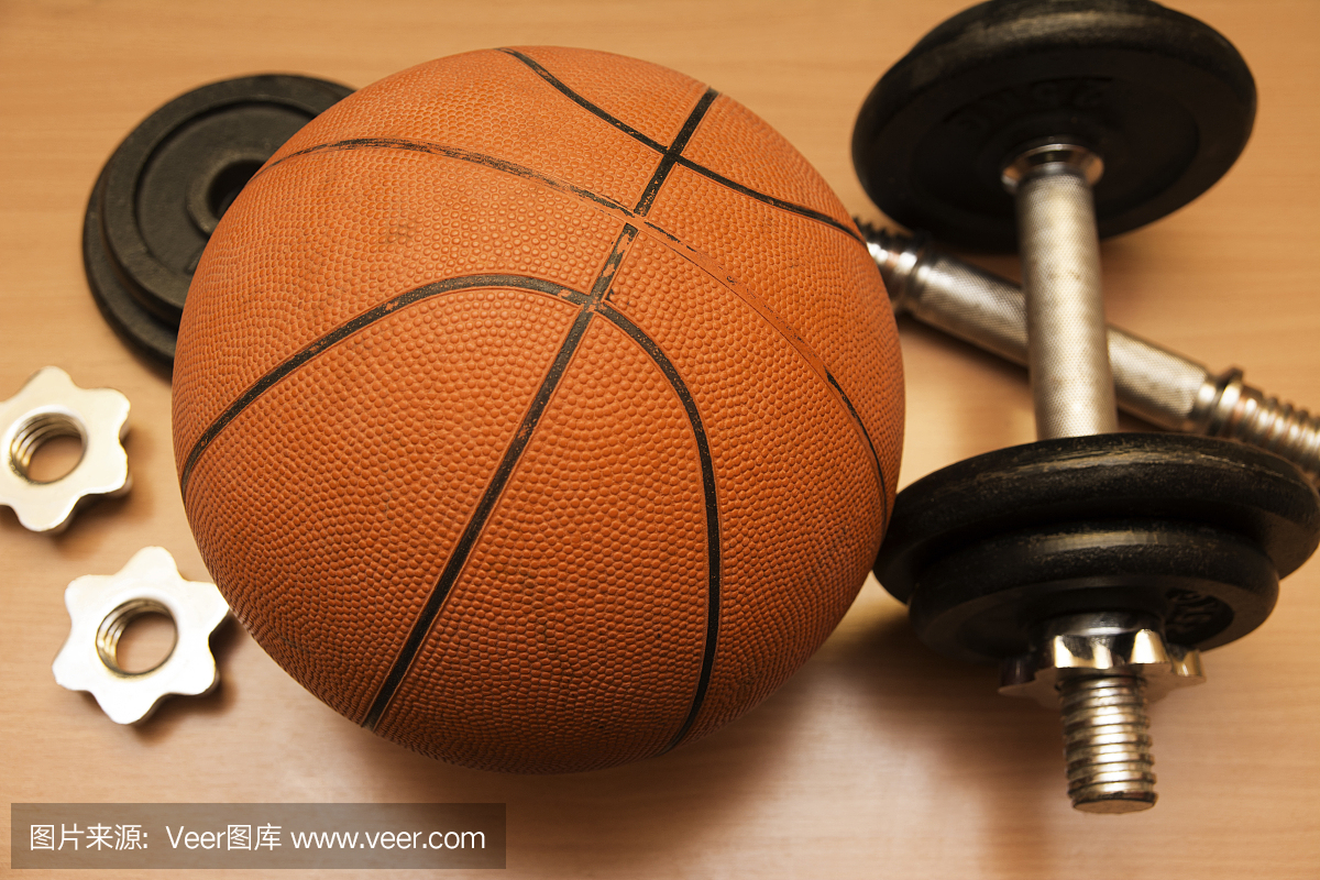 在木健身房地板上的篮球和哑铃特写镜头