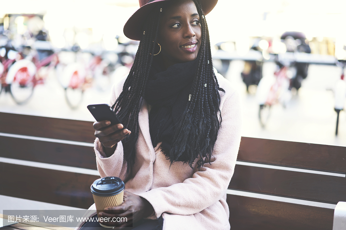 微笑黑人的美国女学生,在现代移动电话上检查