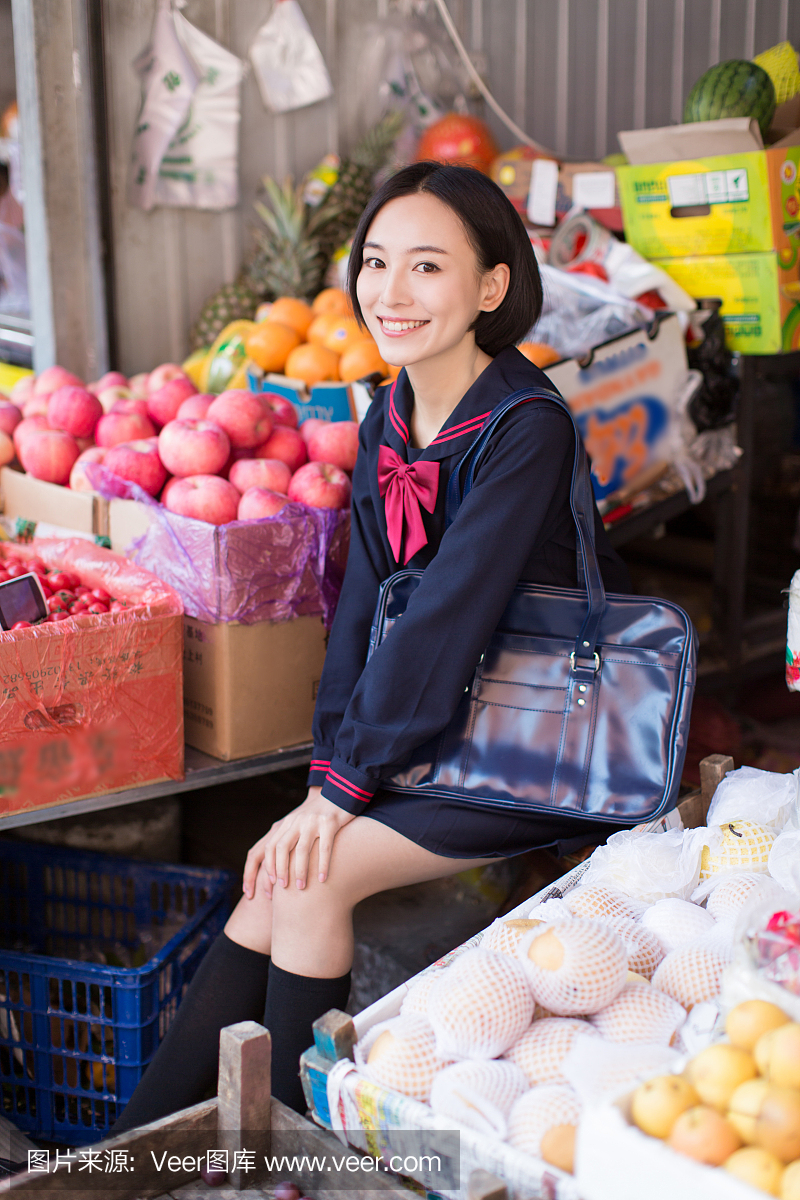 美丽的中国女学生在市场上买水果和蔬菜