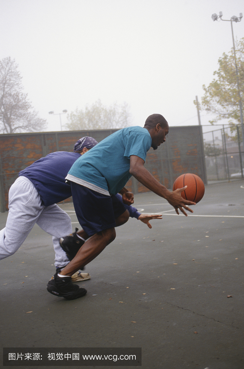 两个年轻人在有雾的公园里打篮球