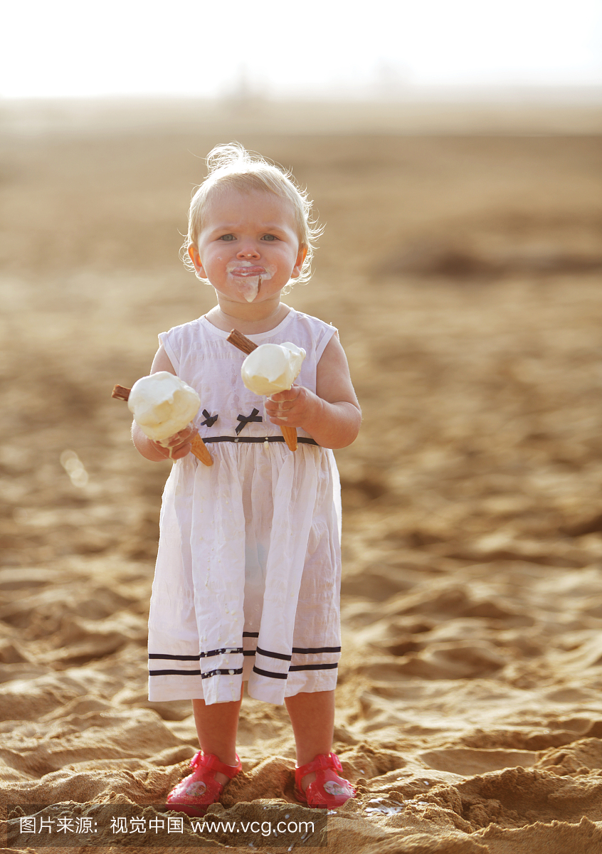 小孩在沙滩上吃两块冰淇淋