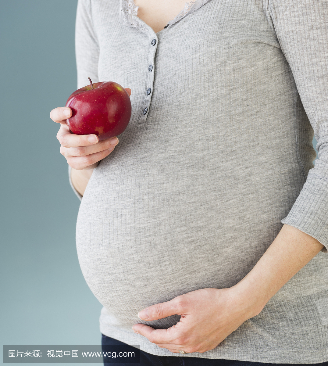 孕妇吃苹果,腹部的工作室拍摄