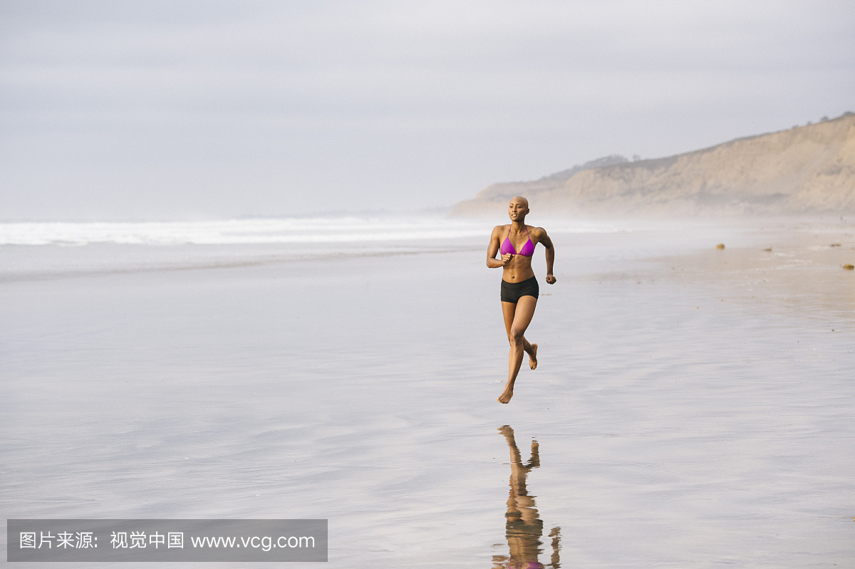 比基尼泳装在沙滩上慢跑的女人