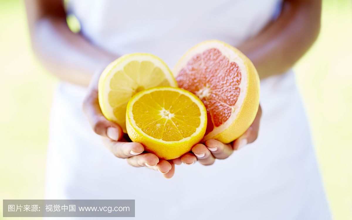 女子手拿着一半的橙子和葡萄柚
