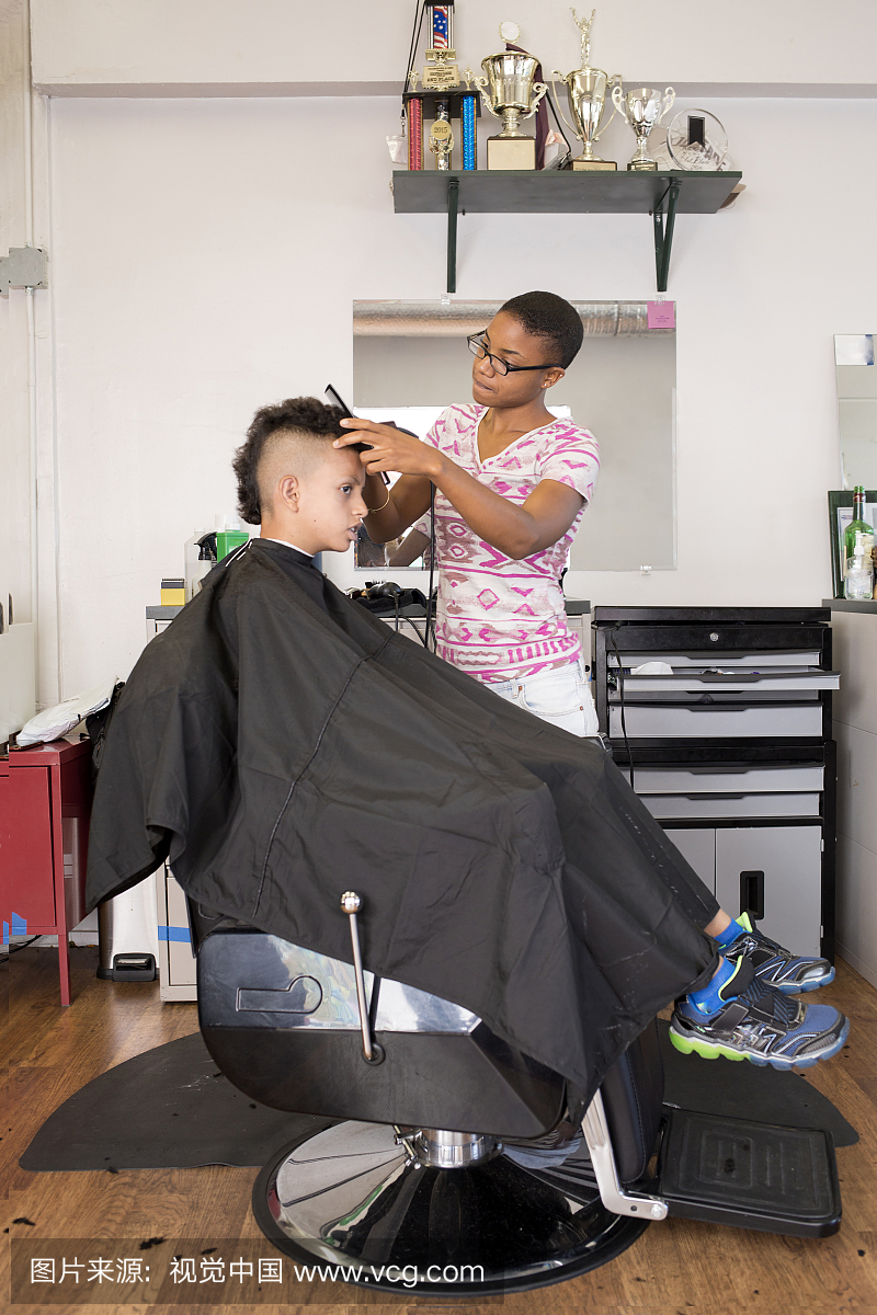 女理发师在理发店的男孩发型上使用理发器