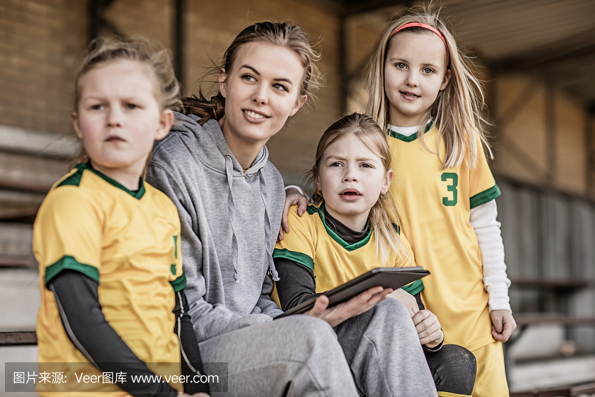 年轻的金发女子足球教练和她的女孩足球队
