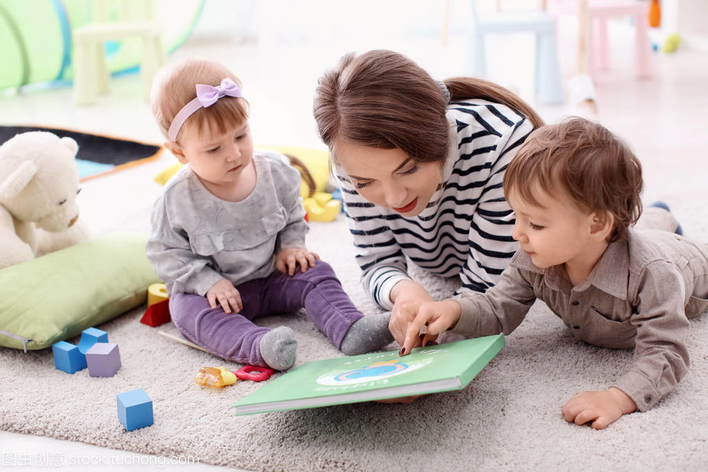 Cute little girl with young nanny at table, indoors Cute little girl with young nanny at table, indoors