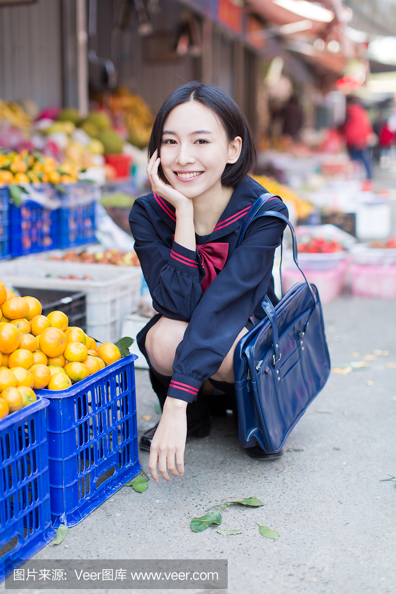 美丽的中国女学生在市场上买水果和蔬菜