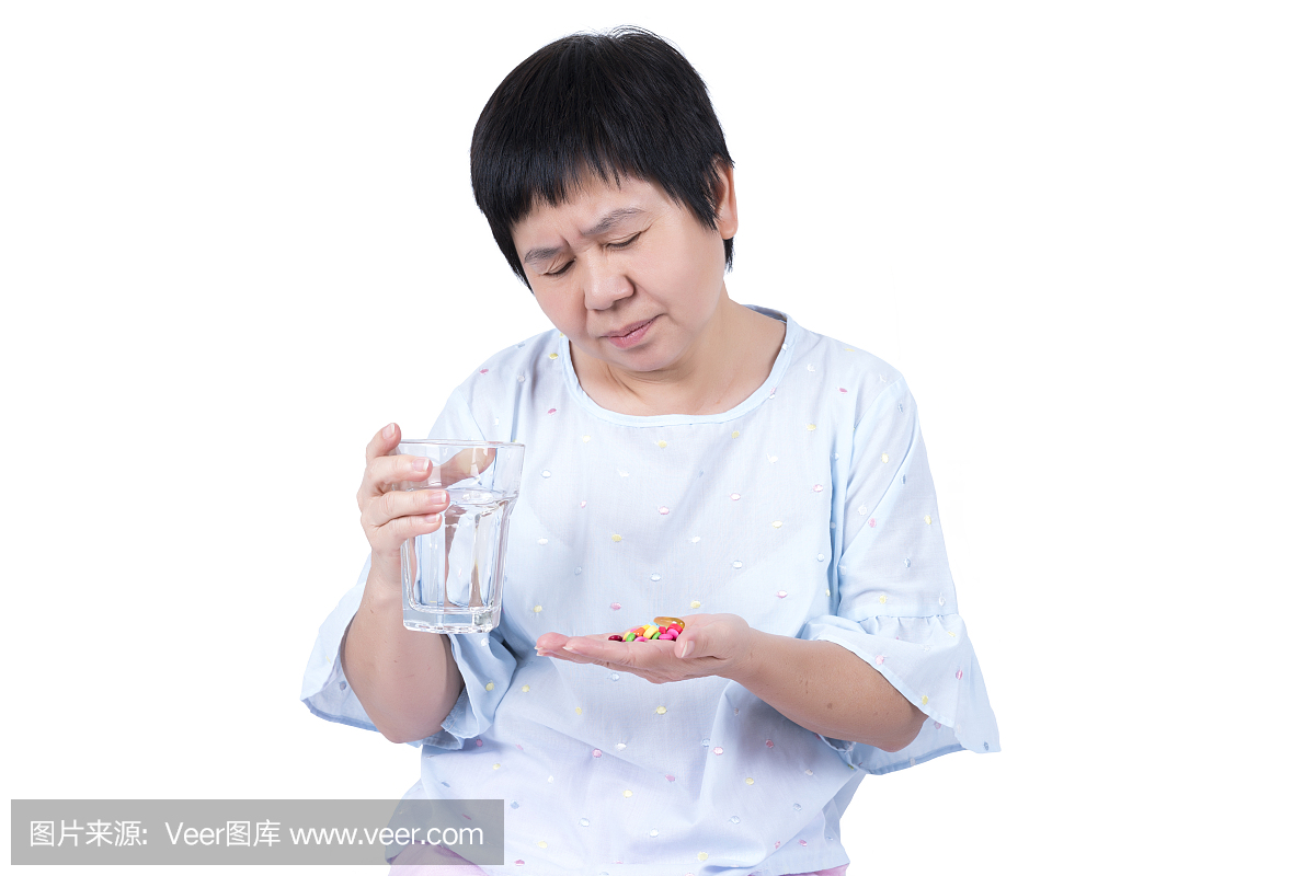 亚洲中年妇女拿着杯水和看很多药片,她必须采