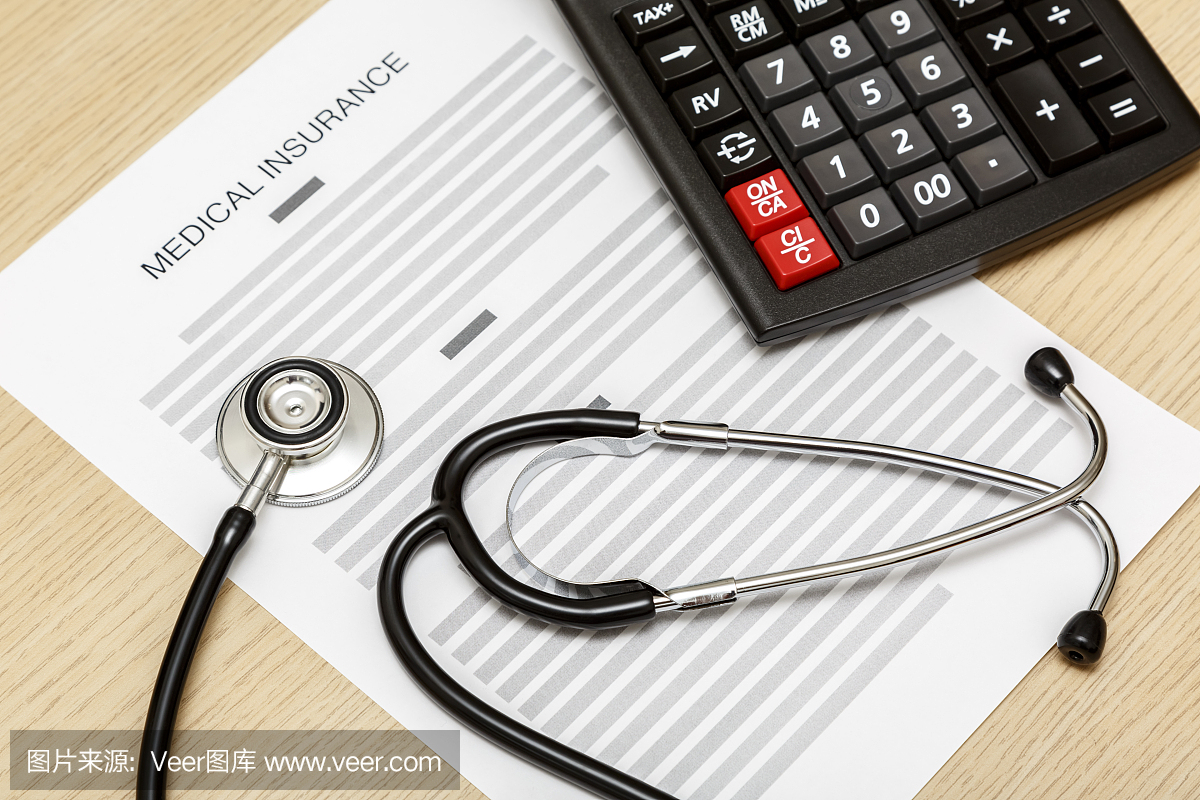 听诊器和计算器放在医疗保险的空白处。