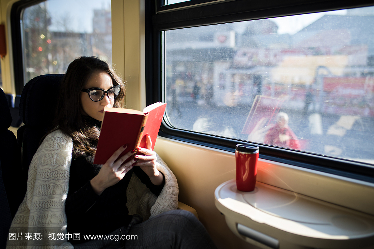 与火车通勤者旅程坐着旅行时阅读的女人