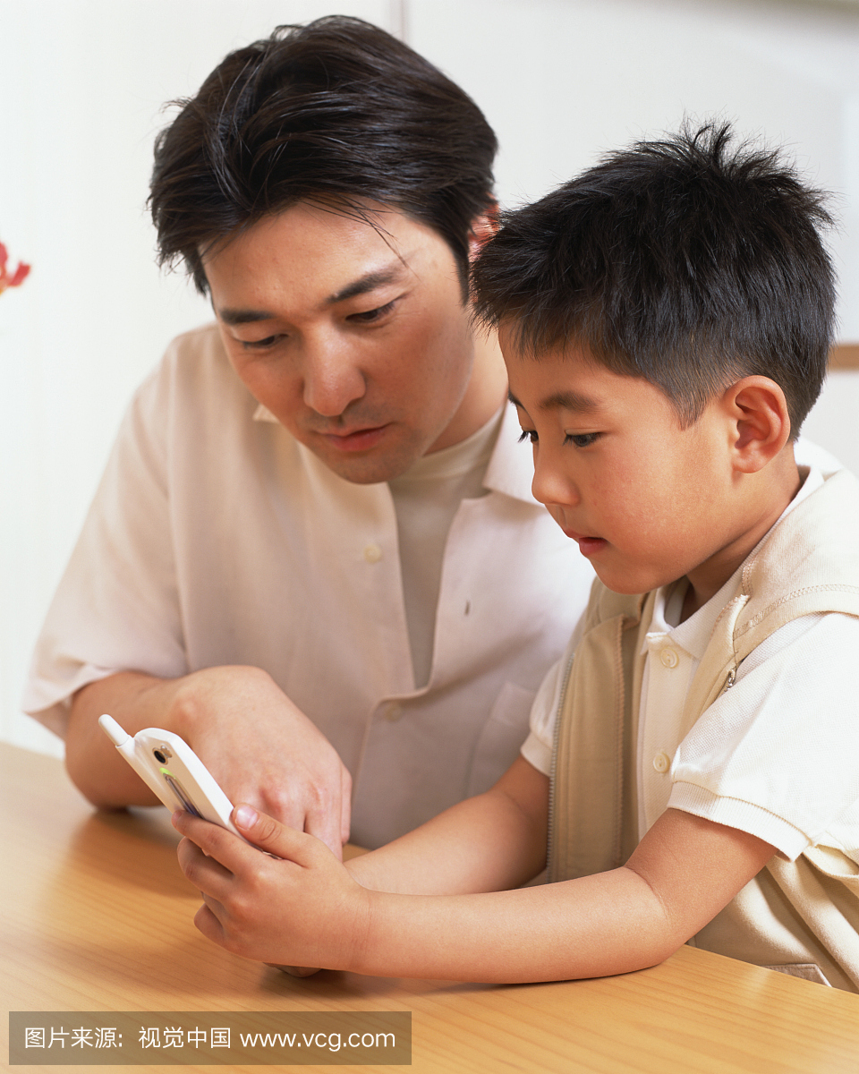 一个小男孩和他父亲一起看手机