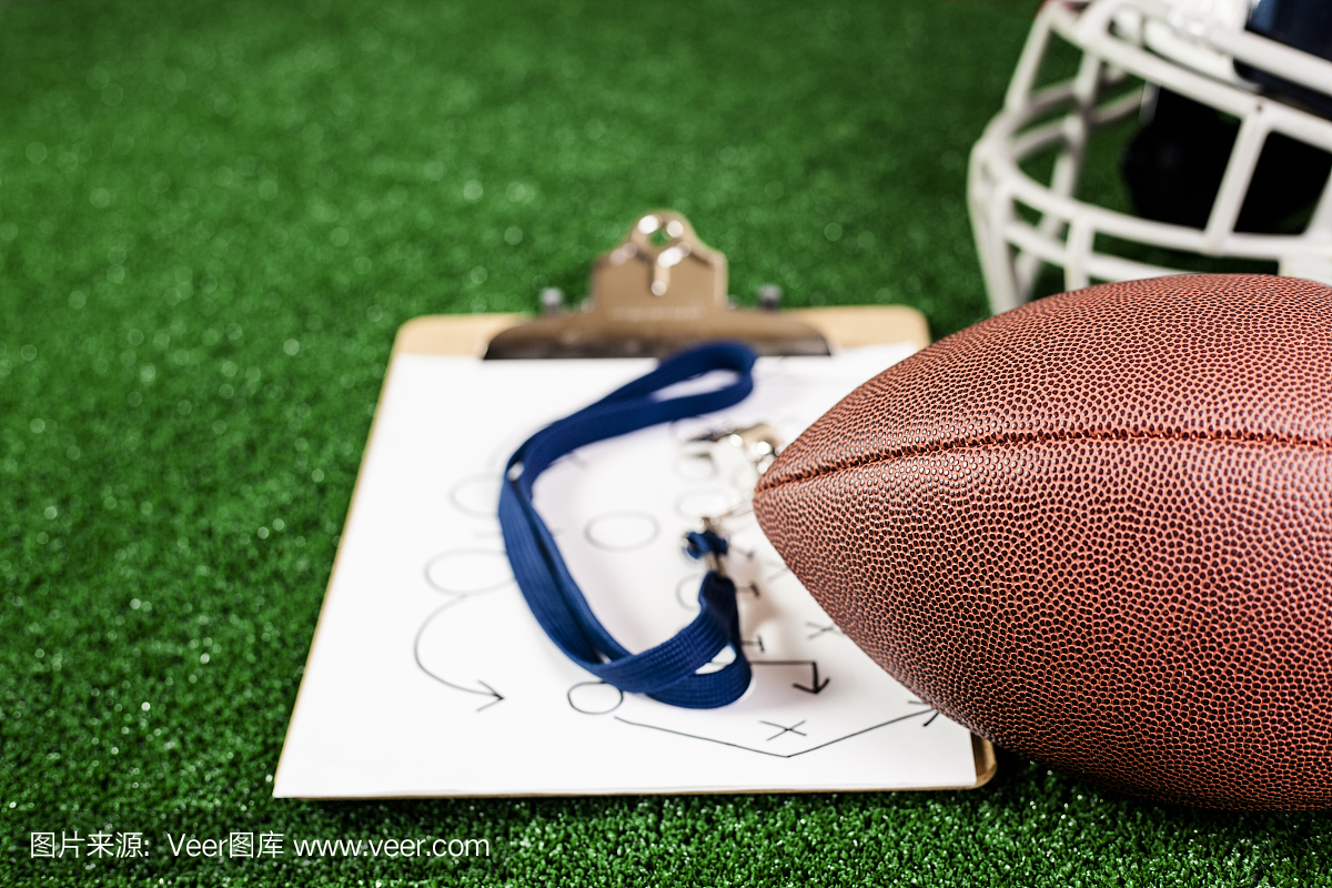 足球教练的口哨,足球,球员的头盔在绿草皮上。