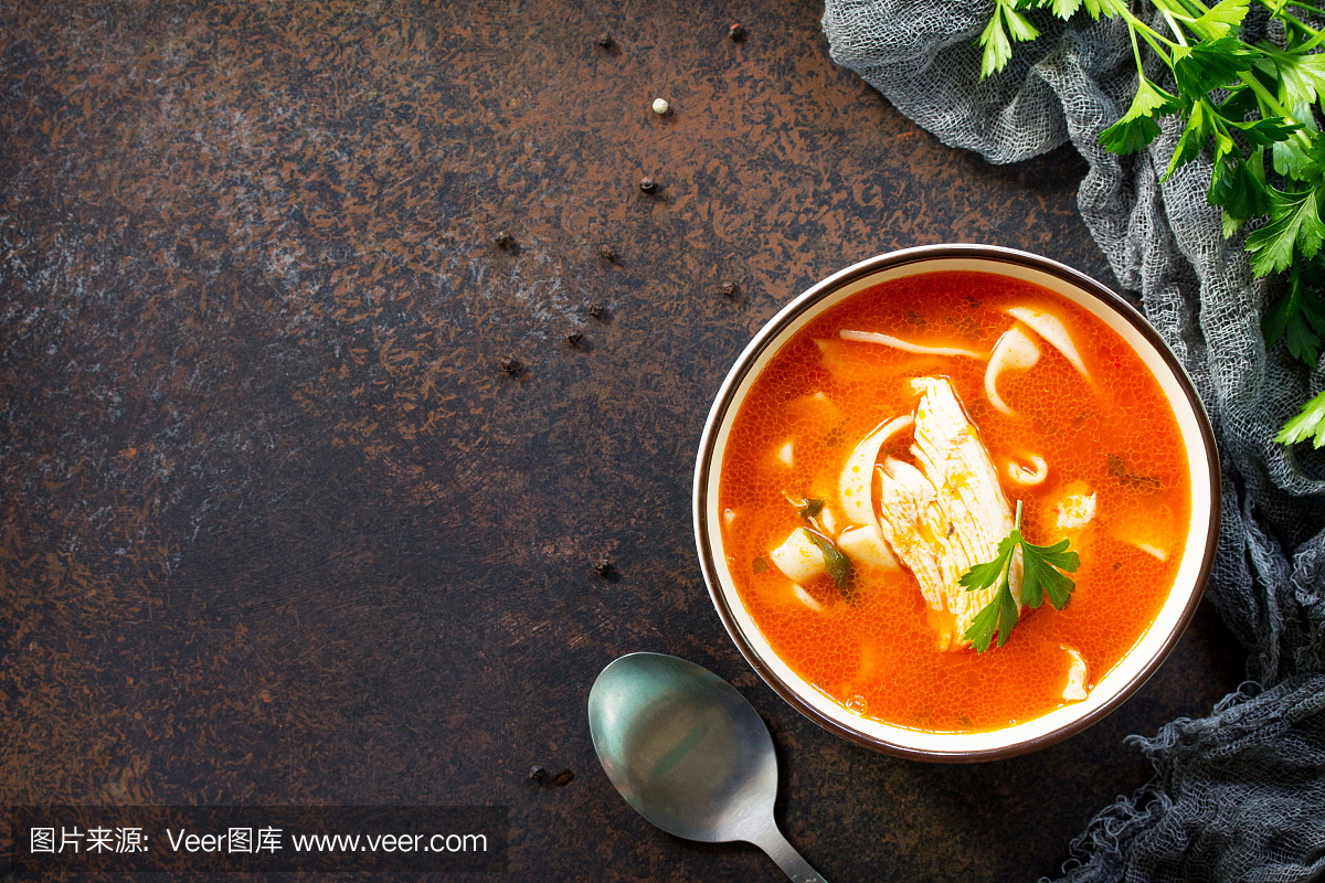 番茄汤配意大利面和鸡在深色石背景上的碗里。