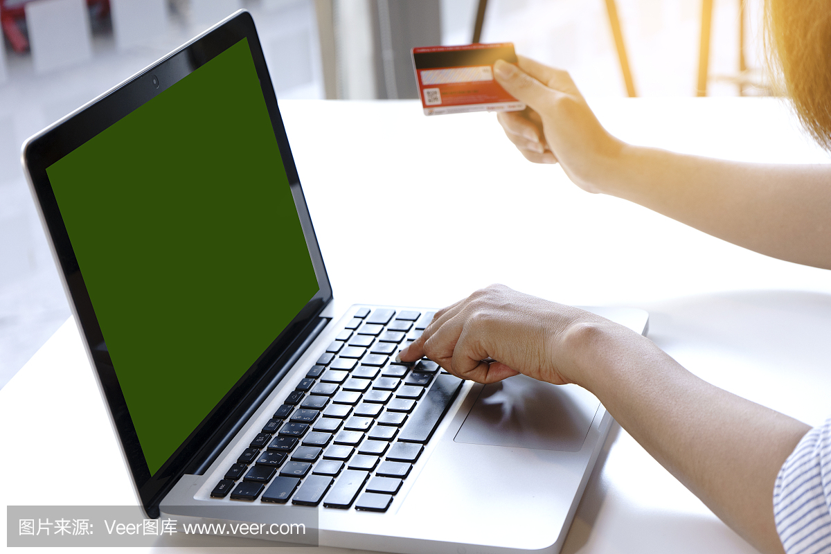 女人坐在使用电脑支付她的网上购物的钱