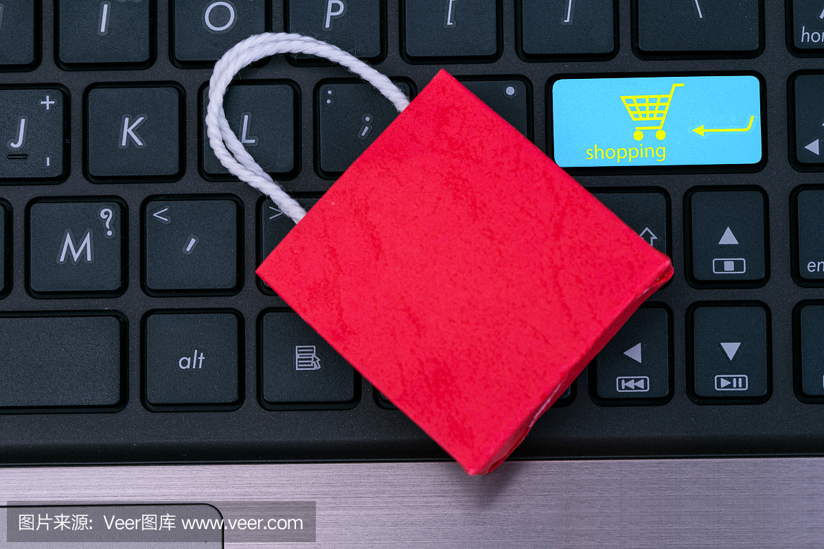 笔记本电脑键盘上的小红纸购物袋。等待客户点