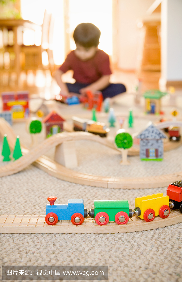 玩具火车设置与3-4岁的男孩在背景中玩