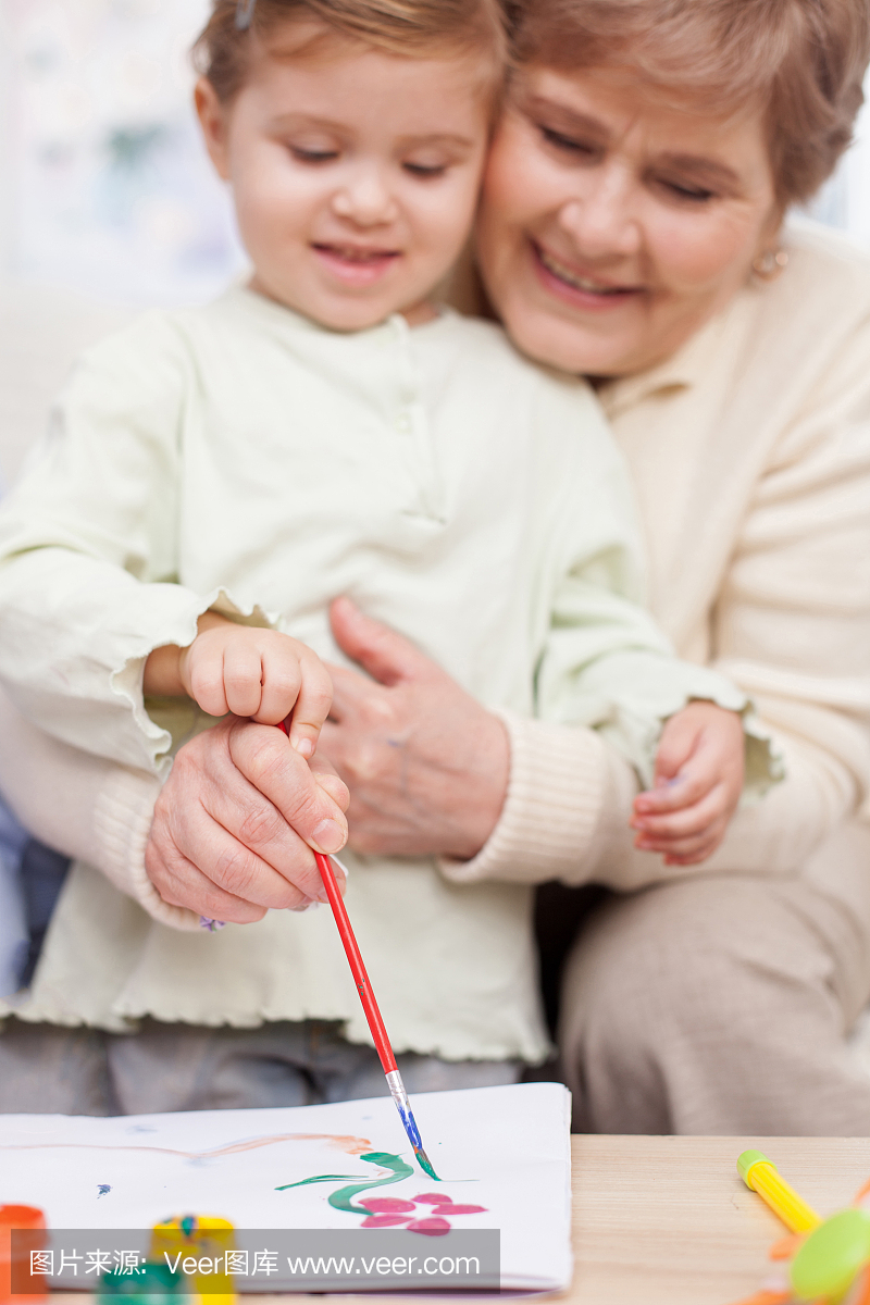 漂亮的祖父母正在教孩子画画